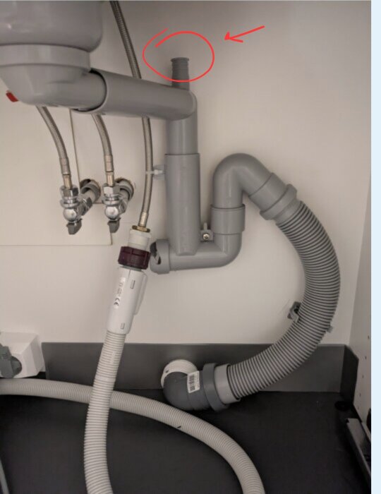 Installationsplats för diskmaskin syns under diskbänken med anslutningsrör markerat med röd cirkel och pil.