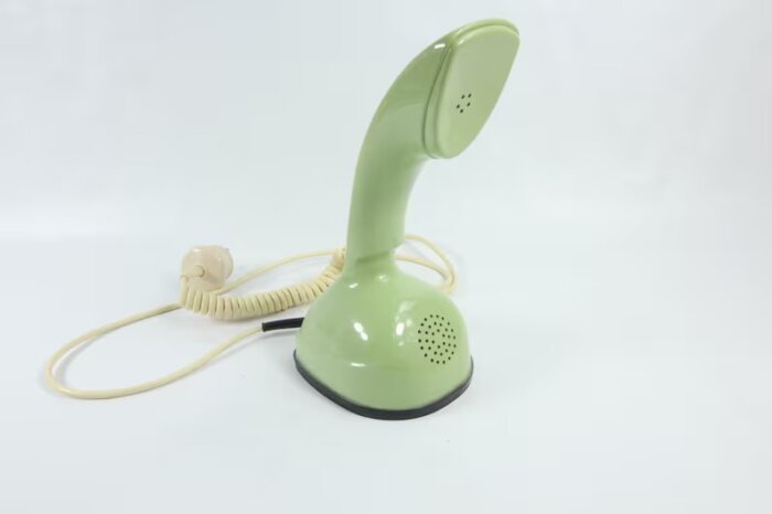 Grön retro telefon med snurrsladd på vit bakgrund.