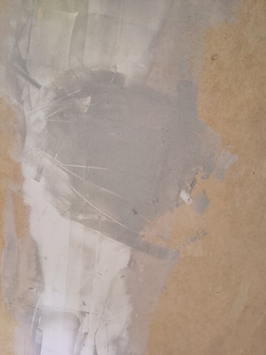Grått och beige väggparti där tapet delvis ångats bort, förbereder för ytskiktsrenovering.