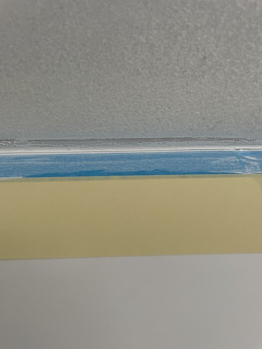 Bilden visar en silikonfog i ett badrum, med tejpade kanter och färg ovanför. Problemet är att färgen inte fäster på silikonet enligt inlägget.