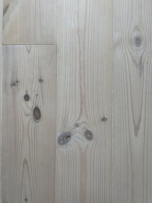 Ljust trägolv med synliga ådringar och kvistar, möjligen mjukt och känsligt för märken enligt trådsammanhanget.