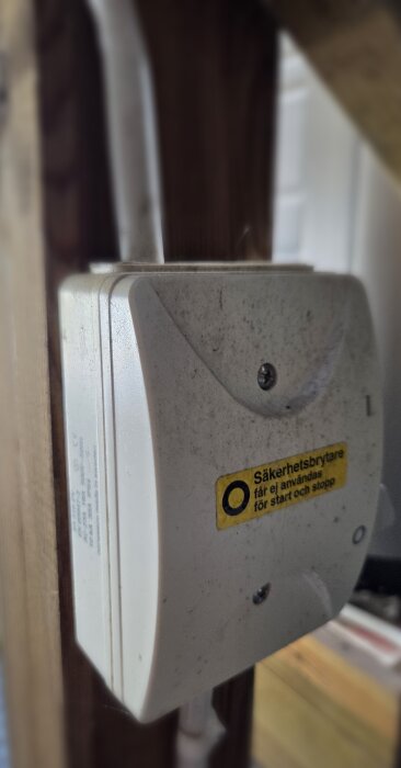 Säkerhetsbrytare monterad utomhus, med etikett som varnar mot att använda den för start och stopp. Brytaren visar tecken på smuts och åldrande.