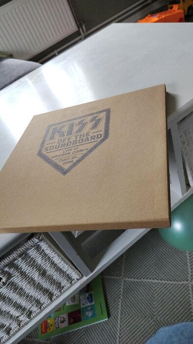 Skivomslag från "KISS Off the Soundboard: Live in Virginia Beach, July 25, 2004" på ett soffbord.