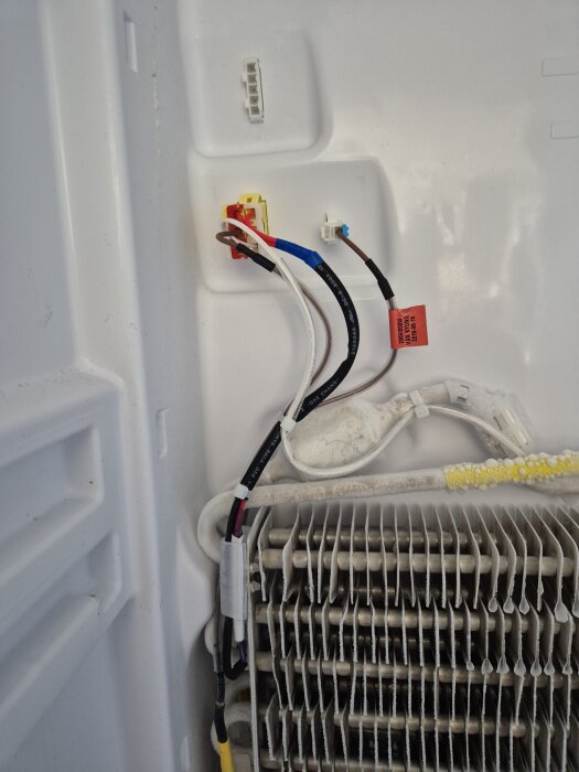 Kablar och frostelement i en samsung frys med avfrostningsproblem. Synlig frost på elementen och anslutna kablar i frysens insida.