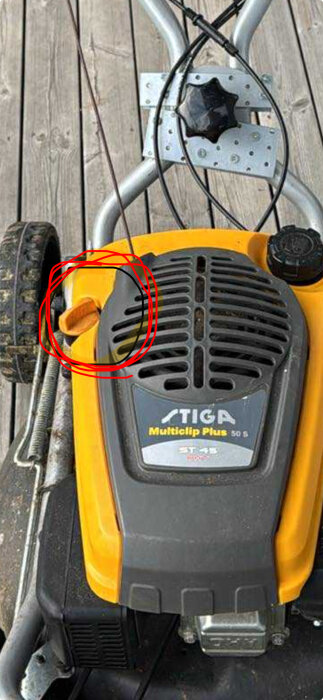 Närbild av en gräsklippares överdel med en oljedipstick markerad med röd cirkel.