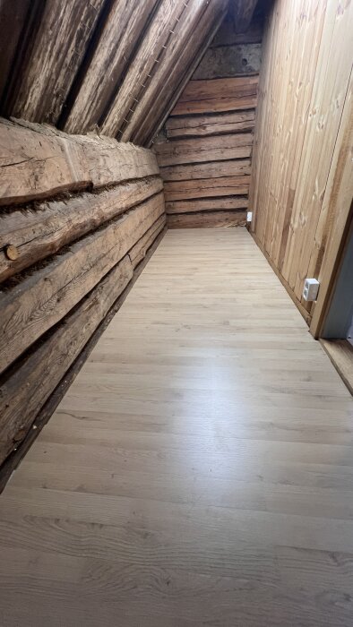 Vinttihuone, jossa on puiset seinät ja tuore laminaattilattia, aiemmin pelottavia lattialautoja korjattu.
