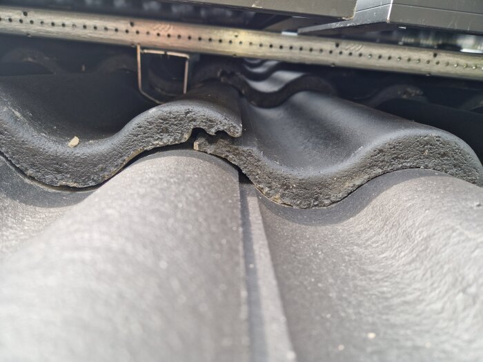 Springa mellan betongtakpannor under solpanelupphängning, potentiell risk för läckage vid takkrok.