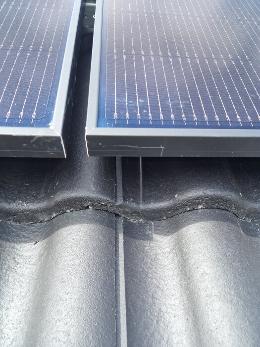 Solpaneler monterade på takpannor med synliga springor mellan pannorna. Möjlig risk för läckage bedöms.