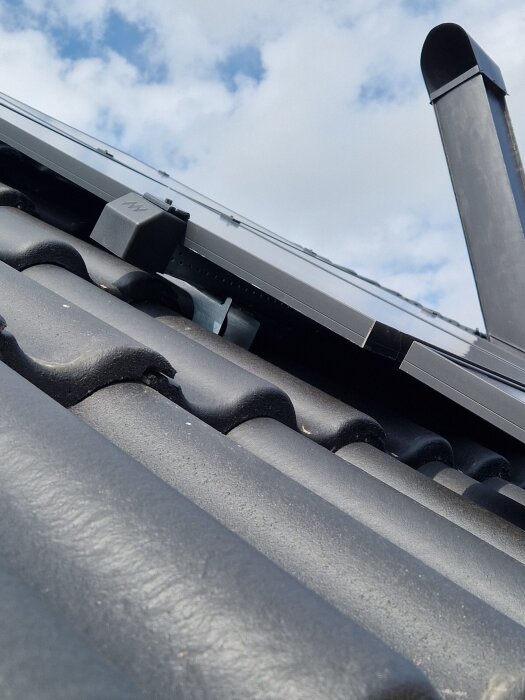 Svart tak med solpaneler, taklutning ca 40 grader. Till höger syns ett svart ventilationsrör.