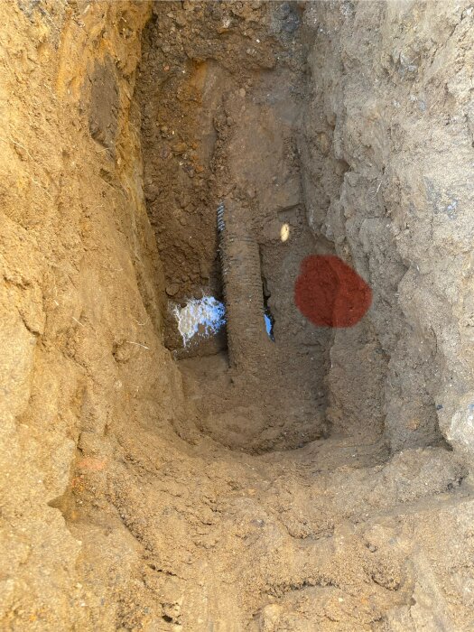 Utgrävd plats i marken med synlig röranslutning, avsedd för att ansluta ett nytt rör från källarbrunnen i ett byggprojekt.