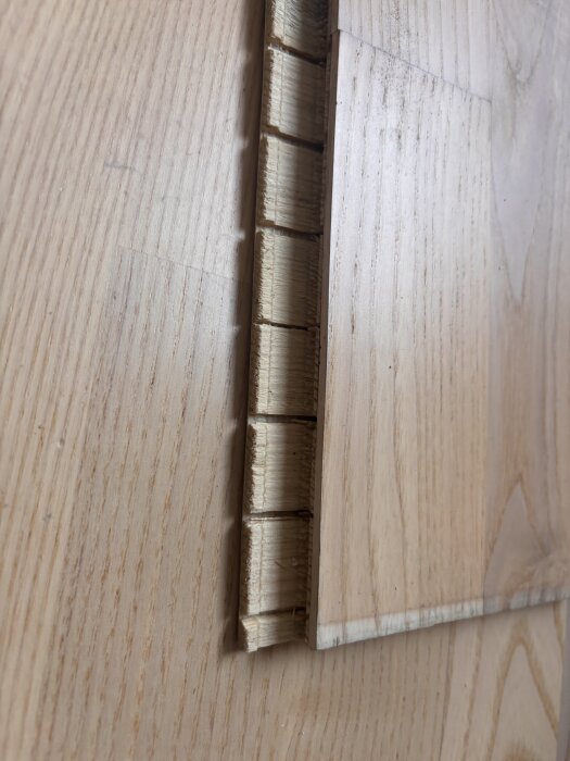 Närbild på en bit vitlaserad ask 3-stav mattlackerad parkettgolv, visande kanterna och strukturen av träet.