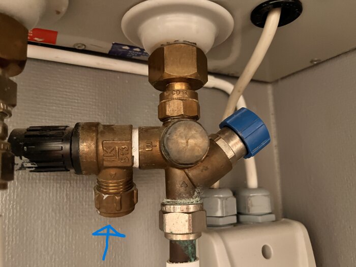 Rörkoppling med blå pil som pekar på en specifik anslutning under diskbänk.