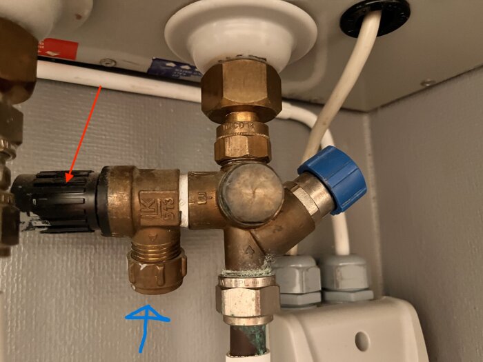 Säkerhetsventil med svart ratt markerad med röd pil och anslutning markerad med blå pil för vattenutsläpp vid övertryck.