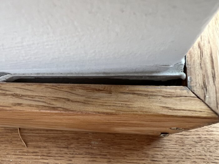 Trälist har delvis lossnat från betongvägg, bilden visar hur listen sitter i hörnet.