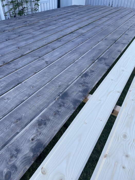 Träpaneler i olika stadier av målning på rad utomhus, redo för ytterligare bearbetning i uppehållsvädret.