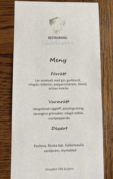 Meny från Restaurang Silverklippan med rätter: lax med gin, hängmörad ryggbiff och Pavlova. Vinpaket 595 kr/person.