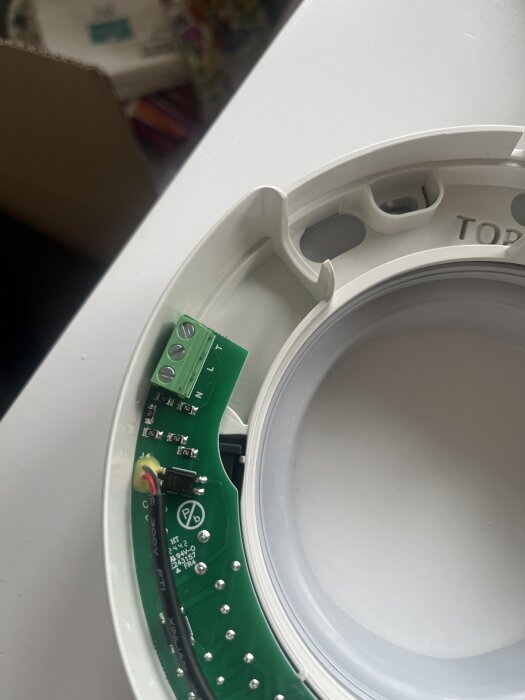 Närbild av insidan på en badrumsfläkt med synliga elektriska kopplingspunkter märkta med L, N och T på ett kretskort.