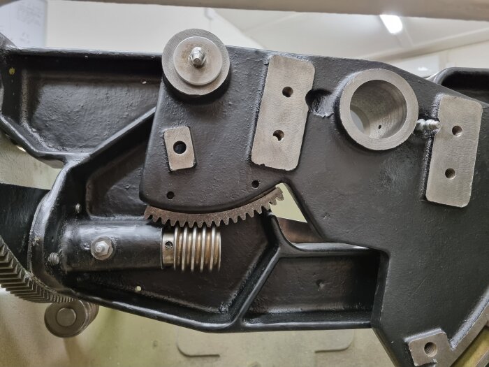 Stålkomponenter i en maskin med kugghjul och nyss målade motorfästen, del av ett byggprojekt med fokus på renovering och uppgradering av utrustning.