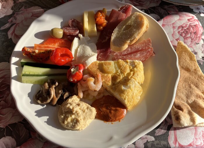Tallrik med diverse tapas såsom salami, ost, oliver, räkor, omelett, bröd och grönsaker. En del av en tapaskväll.