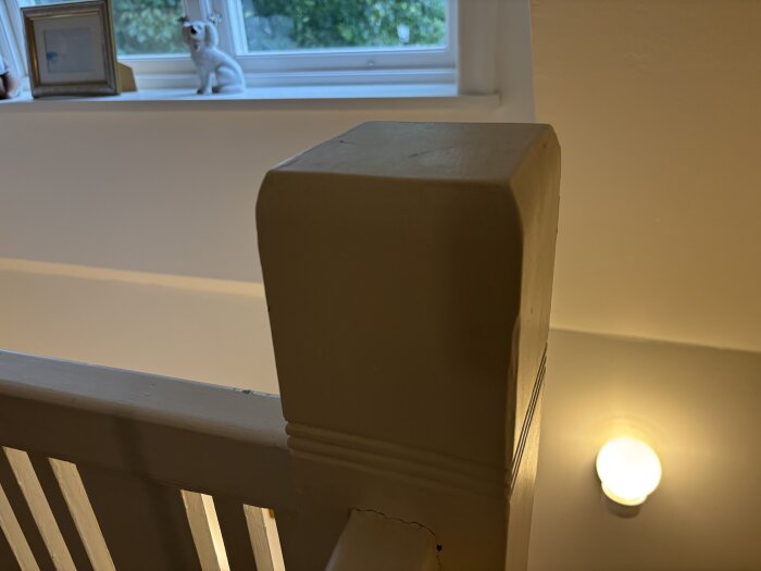 Avfasad trästolpe på toppen av en trappa med ljus i bakgrunden.