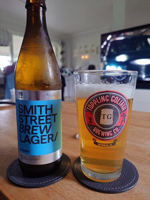 Flaska och glas med öl från Smith Street Brew på ett bord, inomhusmiljö med TV i bakgrunden.
