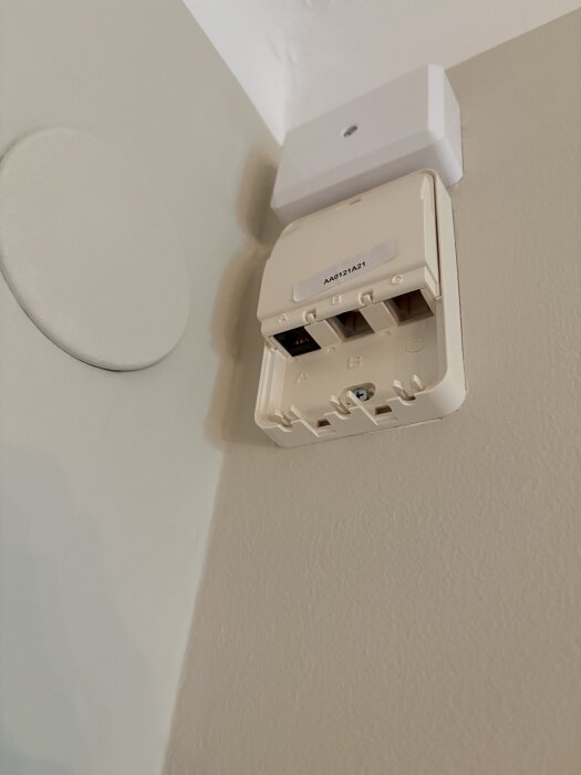 Inkommande anslutningspunkt för fiber på vägg med öppen lucka, märkning "AA.0121A21" synlig.