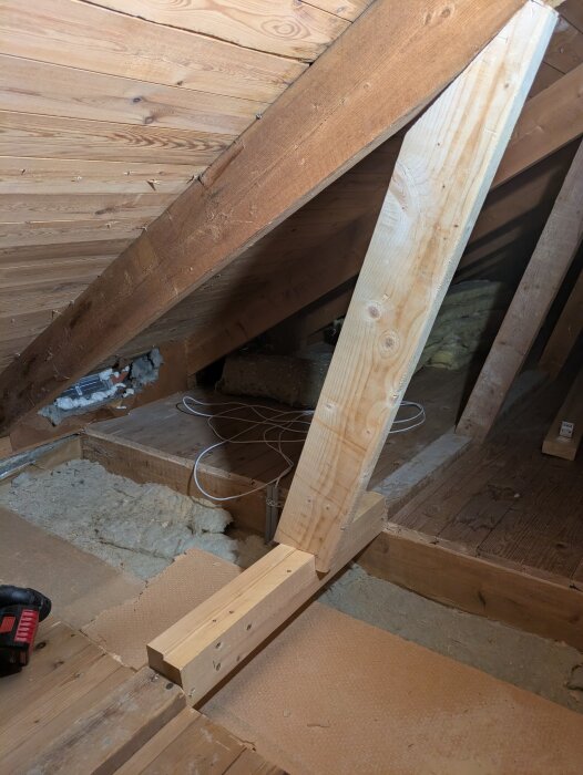 Sektion av bjälklag under renovering med ny takstötta av trä och synliga VP-rör för nätverk.