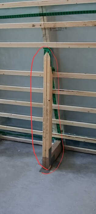 Dubbla takstolar med plattjärn emellan, placerade mot en vägg med träreglar och gröna distanser, markerade med röd linje.