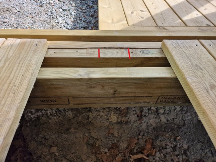 Byggprojekt: Altanbjälklag med en regel markerad med röda streck, omgiven av trätrall. Fråga om att modifiera konstruktionen för stolpmontering.