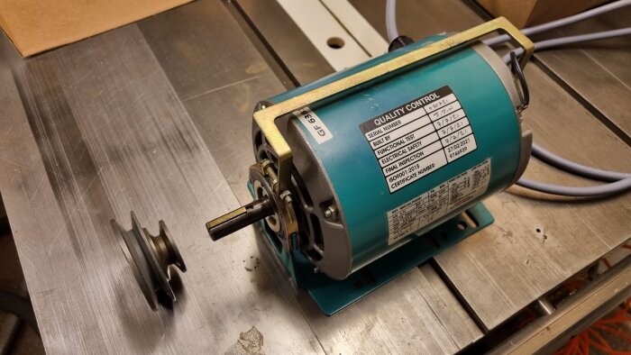 Motor på arbetsbord, med etikett för kvalitetskontroll och en remskiva.