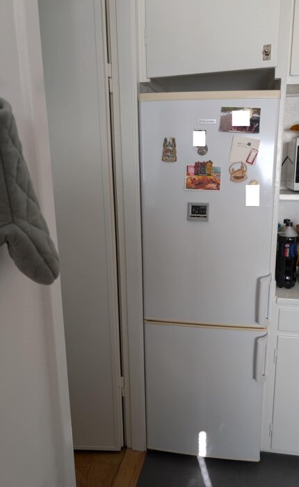 Vit Electrolux kyl/frys med magneter, placerad i ett trångt kök med skåp ovanpå.