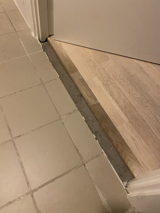 Badrumströskel med glipa mot klinkersgolv, visar behov av en djupare tröskel för att täcka hela avståndet mellan dörr och klinkers.