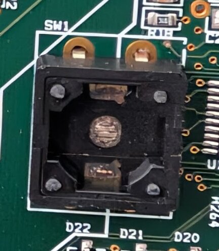 Närbild av en tryckknapp på ett kretskort, troligen en Tamper Switch som saknas komponenter.