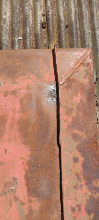 Rostig och skadad metallplatta med flera små hål, placerad på en korrugerad yta.