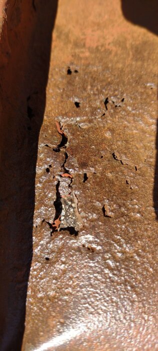 Rostigt tak med flera små hål och sprickor, troligtvis där ett balkongräcke har suttit.