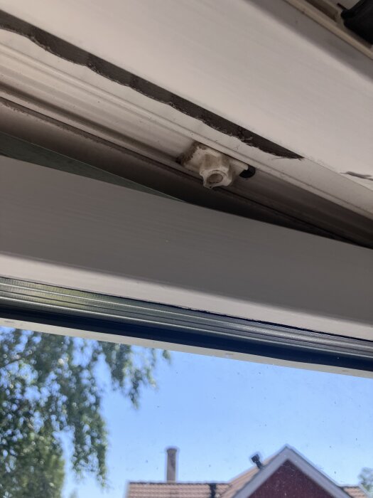 Fönsterskena med synligt slitage och skruvfäste, potentiellt problemområde.