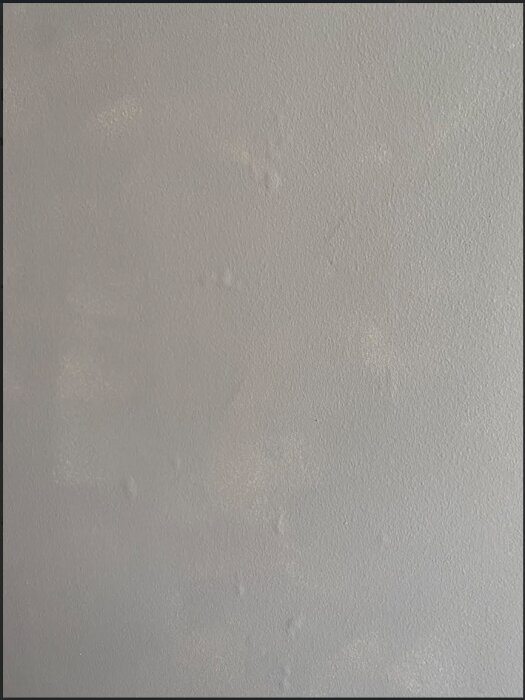 En vägg med små, luftfyllda blåsor under ytan, potentiellt orsakade av regn innan målning.