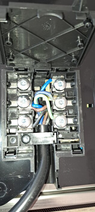 Elektriska anslutningar och färgkodade kablar på undersidan av hällen.