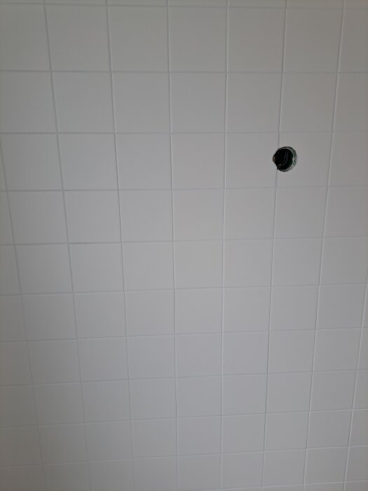 Vitt kakel med hål för installation, slät yta visas i nära plan.