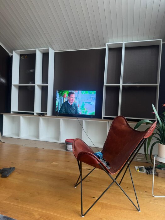 Platsbyggd bokhylla med IKEA Bestå och Billy, TV i mitten, röd läderstol framför.