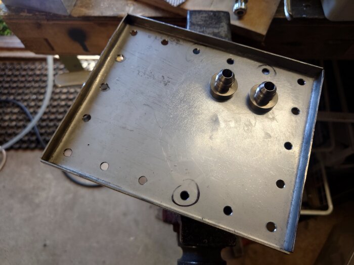 En metallplatta med borrade hål och två metallkopplingar monterade upptill.