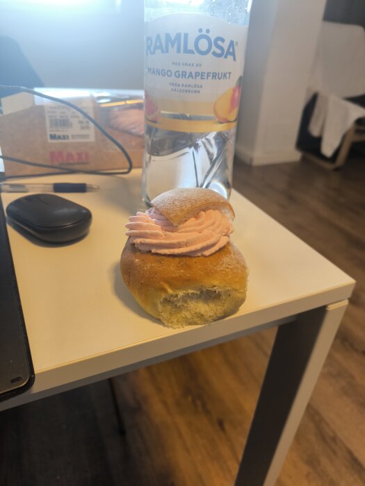 Sommarsemla med rosa grädde och en Ramlösa-flaska på ett bord, Ica Maxi Uppsala syd.