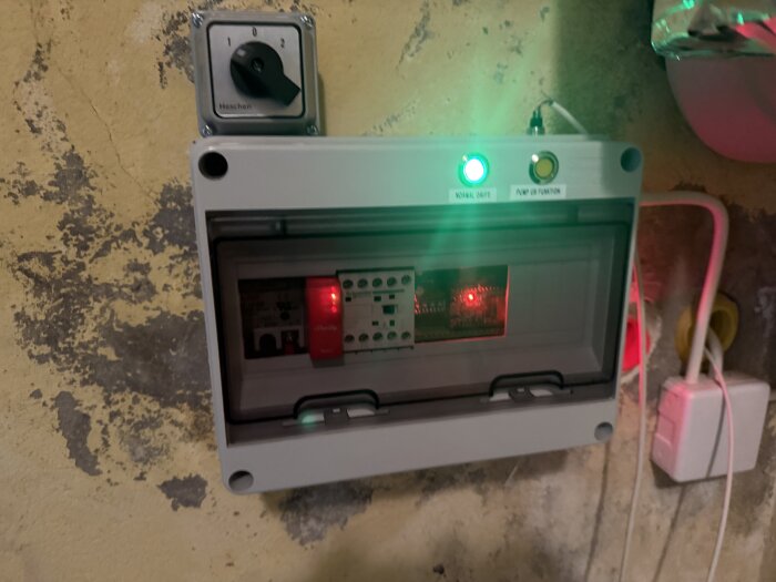 Kontrollpanel med belysning och reglage för en dräneringspump, monterad på en vägg med sladdanslutning.