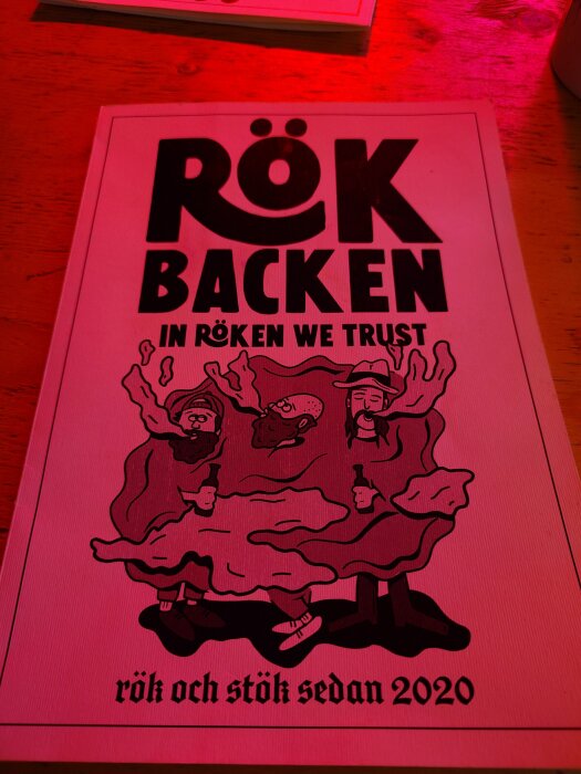 Meny från RöK BaCkEn med slogan "In röken we trust" och illustration av tre personer inneslutna i rök, samt texten "rök och stök sedan 2020".