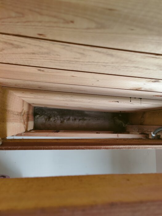 Närbild av en luftspalt och träreglar i en byggnadsstruktur, med synliga träplankor och ett ventilerat utrymme i ett hus.