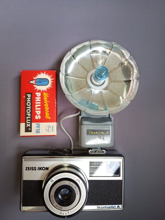 Zeiss Ikon kamera med en fotoblixt och en förpackning Philips Photoflux PFB. Blixtlampan sitter i en reflektor bredvid kameran.