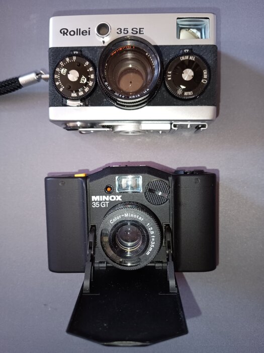 Två vintage kameror: en Rollei 35 SE och en Minox 35 GT, placerade på en plana yta med detaljerade linser och reglage synliga.