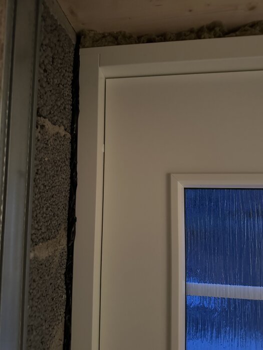 Ytterdörr i källare med murade väggar och isolering synlig ovanför. Fråga om grön tätningstejp och användning för att täcka springa.