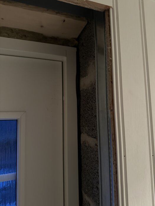 Ytterdörr i källare mellan murade väggar, visar springa utan grön tätningstejp eller isolering runt dörröppningen.