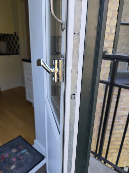Balkongdörr med silverfärgad handtagsmekanism och låsanordning, svår att öppna för rengöring av insidan.